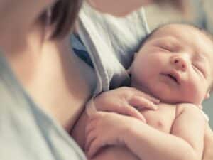 New born baby boy resting in mothers arms.