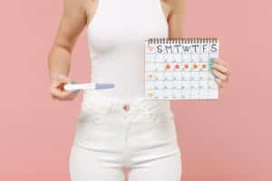 A woman holding a calendar to track vaginal discharge throughout the menstrual cycle