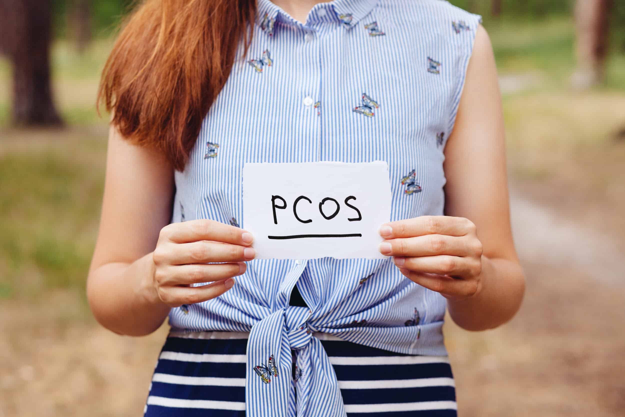 Pcos,-,Polycystic,Ovary,Syndrome,,Woman,Hormone,Sickness,Lettering,On A woman holding a piece of paper that says "PCOS"