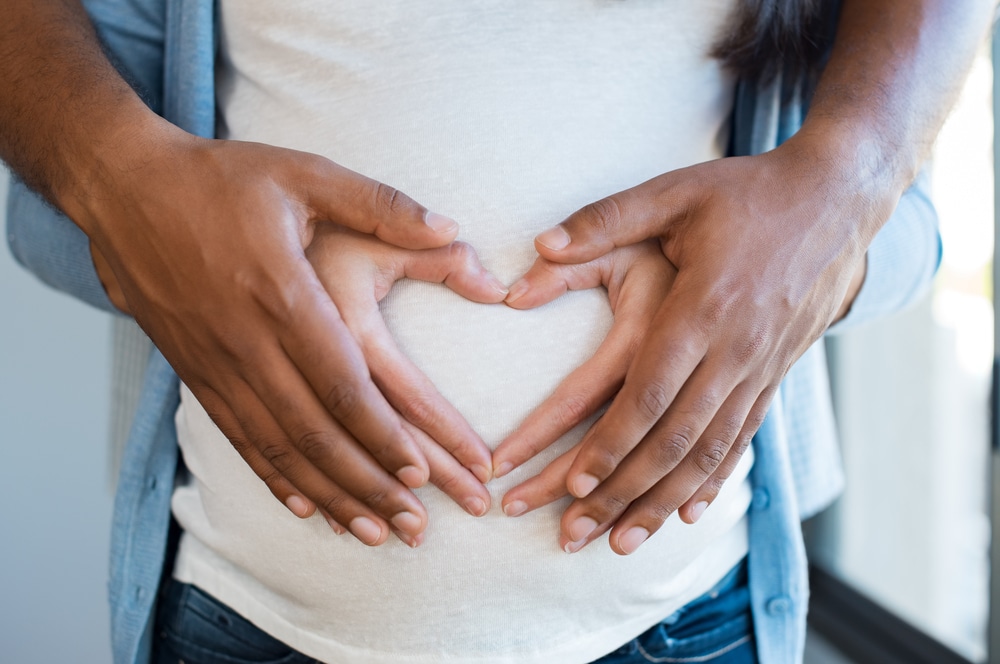 Black,Man,Holding,Belly,Of,His,Pregnant,Wife,Making,Heart. Genetic Testing in Houston, TX