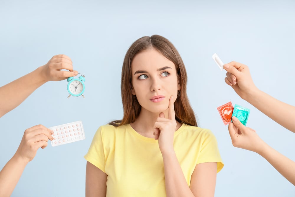 Thoughtful,Young,Woman,And,Hands,With,Different,Means,Of,Contraception A woman considering different birth control options in Houston